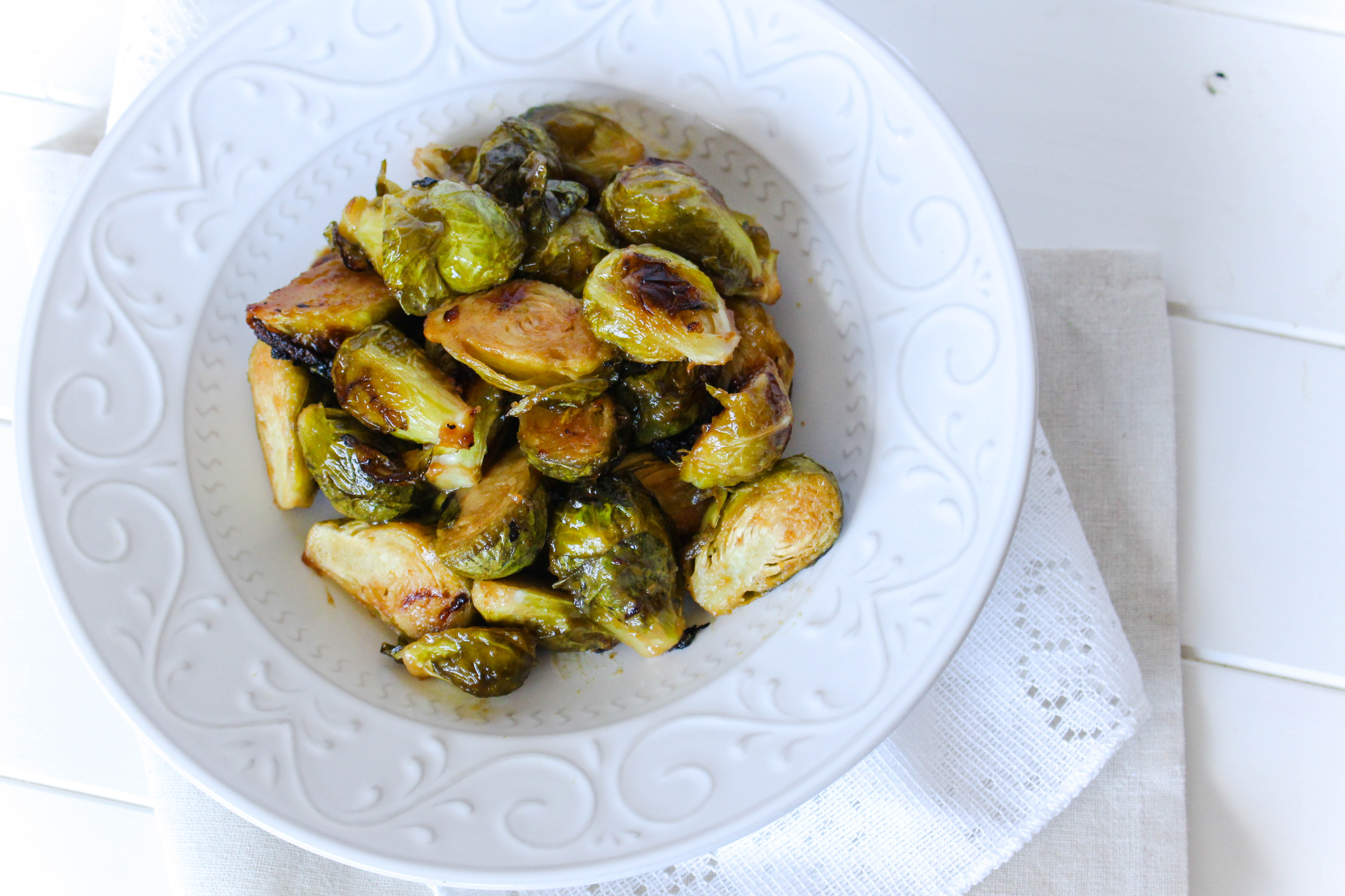 top shot of roasted maple mustard brussels sprouts in a white bowl