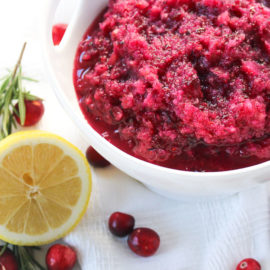 Cranberry Relish in a white dish and fresh cranberries, lemon, and rosemary