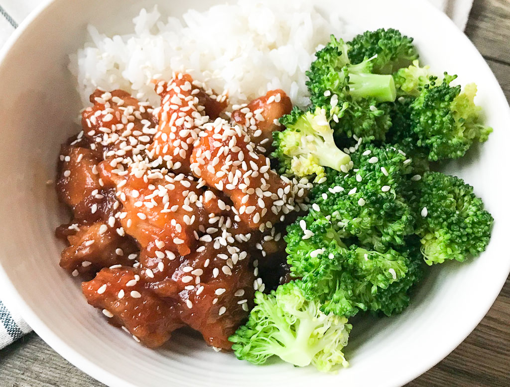 Instant Pot Sesame Chicken in a white bowl with broccoli and rice