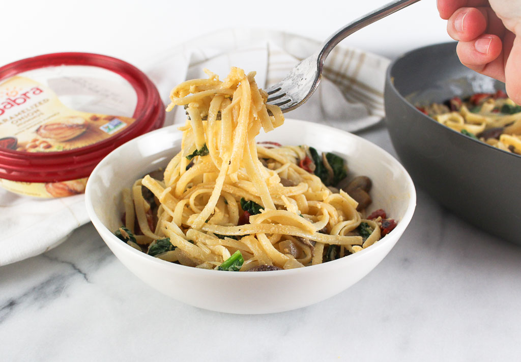 creamy pasta in a white bowl with mushrooms, spinach, roasted red peppers, caramelized onions, and parmesan cheese