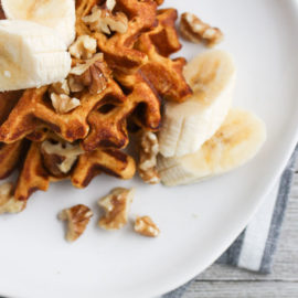 sweet potato waffles on a white plate with bananas and walnuts